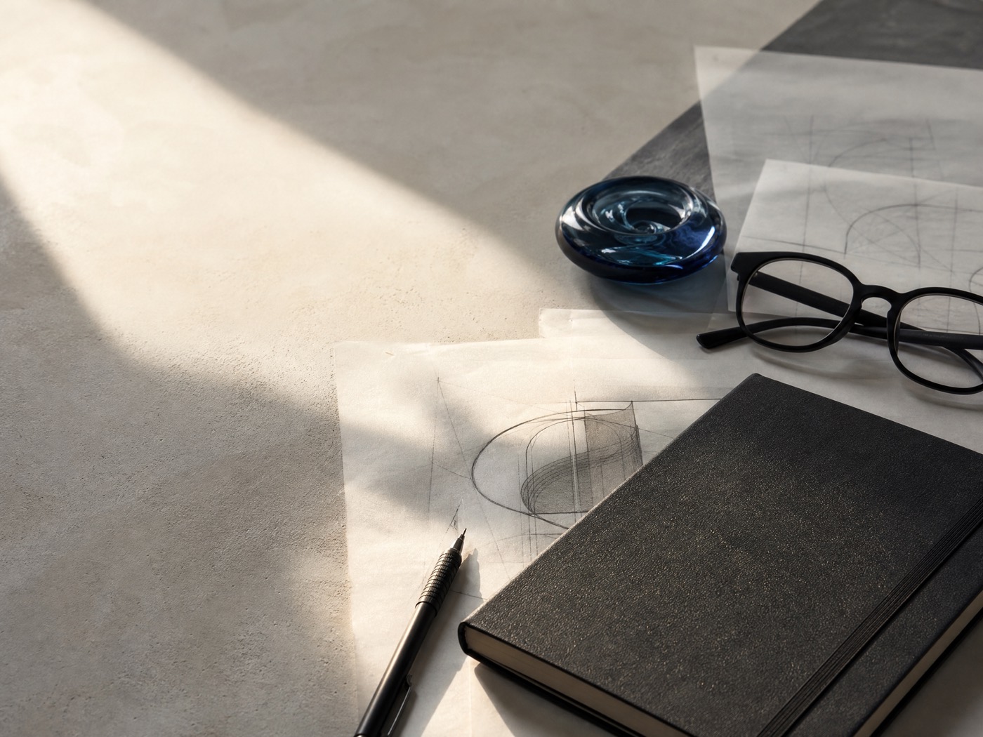 A composed workshop desk with notebook and tracing paper